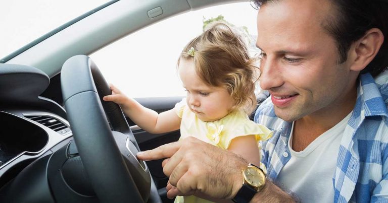 dad showing steering wheel to daughter