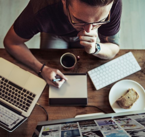 man reviewing data at desk from digital command center